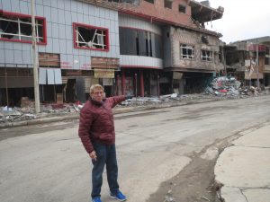 William J. Murray stands outside a building in Qaraqosh that had been destroyed by IS militants.
